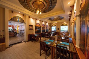 A restaurant with wooden tables and chairs, decorative ceiling, and murals on the walls. - Horizon Karon Beach Resort & Spa (Karon)
