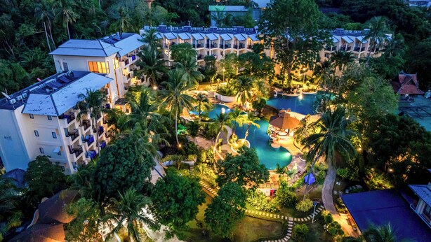 Een resort met meerdere gebouwen, een centraal zwembad en omliggend groen.