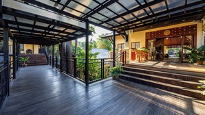 A covered wooden deck with steps leading to a building entrance, surrounded by greenery. - Horizon Karon Beach Resort & Spa (Karon)