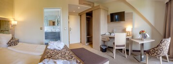 Ein Hotelzimmer mit Bett, Schreibtisch, Stuhl, Fernseher und Kleiderschrank.