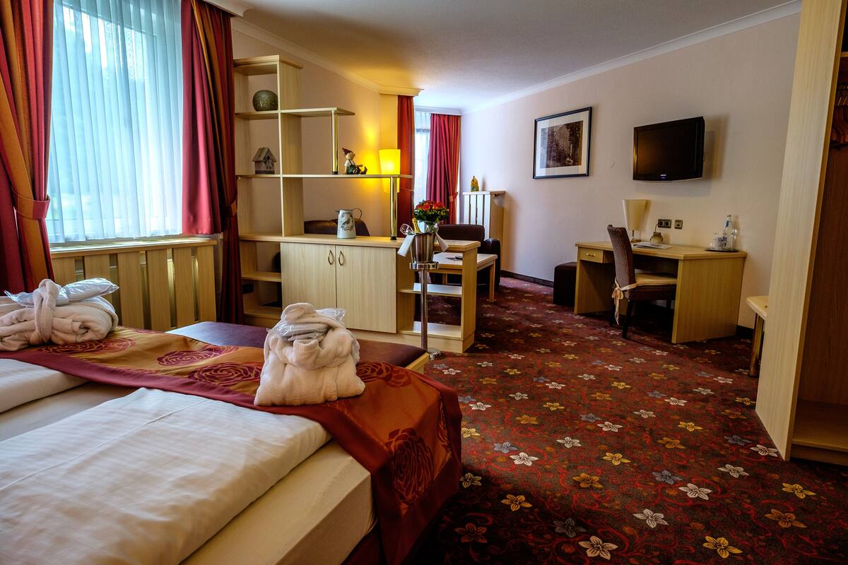 Een hotelkamer met een bed, een bureau, een stoel, een televisie en een vloerbedekking.