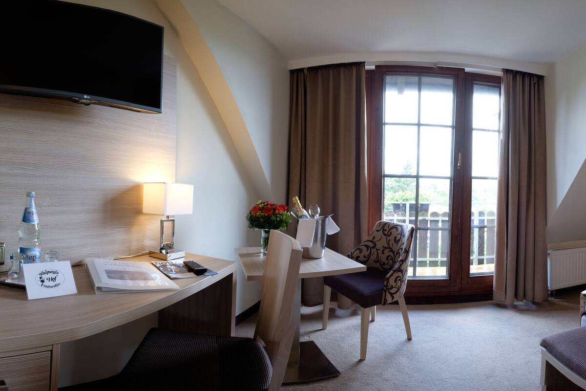 Een hotelkamer met een bed, een bureau, een stoel, een televisie en een raam met gordijnen.