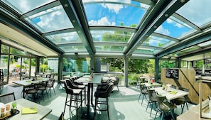 Un restaurante con techo de vidrio, mesas al aire libre y vistas al cielo.