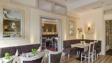 A restaurant with a modern interior, featuring a mix of seating options including booths and tables, with a visible kitchen area in the background.