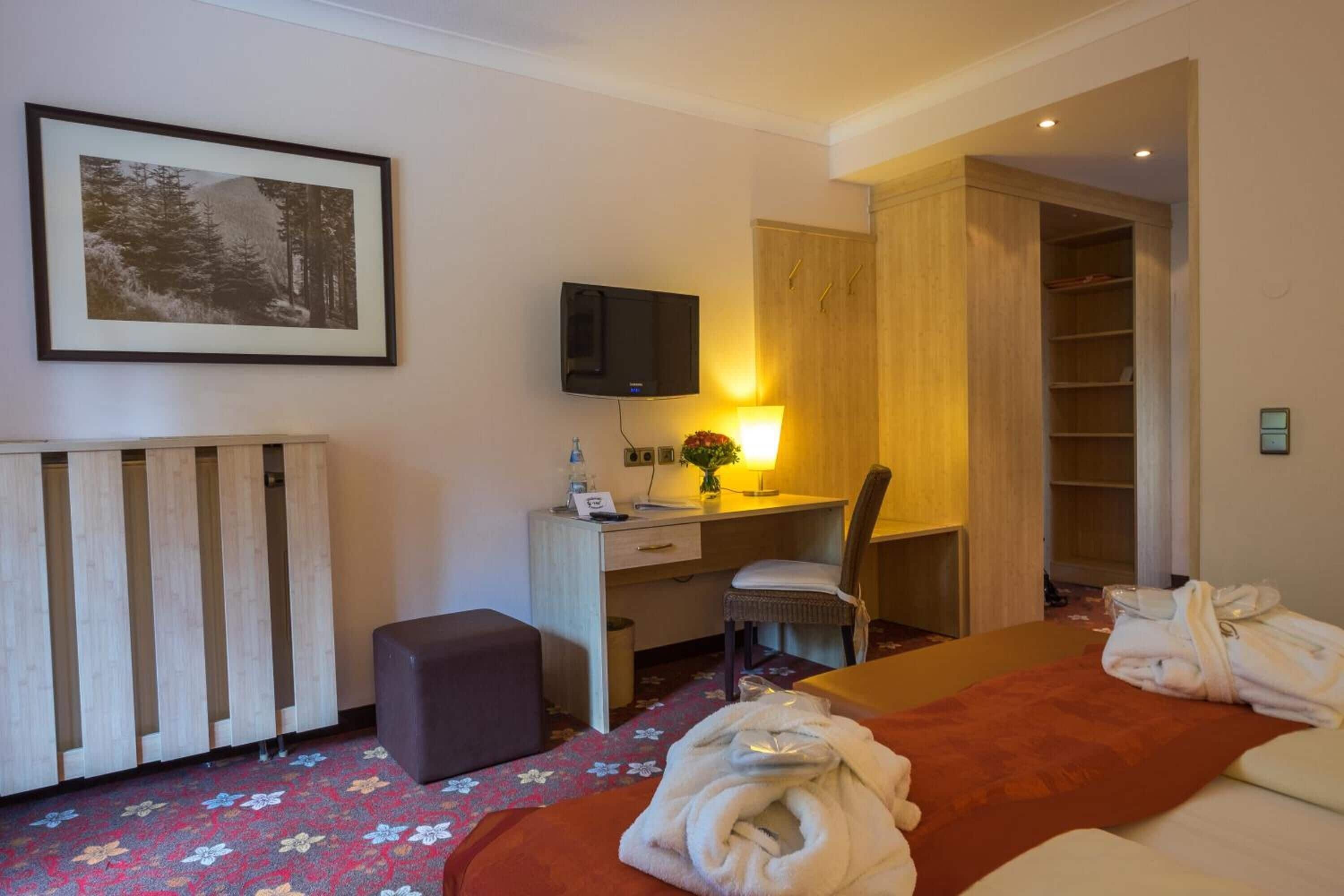 Ein Hotelzimmer mit einem Bett, einem Schreibtisch, einem Stuhl, einem Fernseher und einem Kleiderschrank.