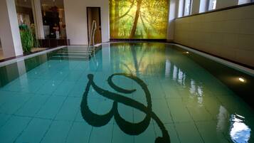 Una piscina interior con un gran mural de una escena boscosa en una pared.
