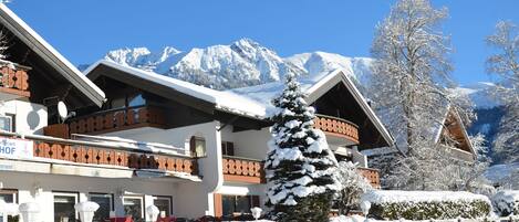 Um edifício coberto de neve com um café e um restaurante, rodeado por neve e montanhas.