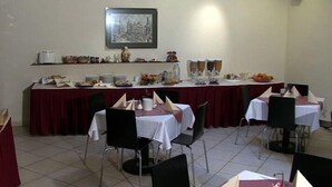 A dining area with tables set for a meal, chairs, a buffet counter, and a framed picture on the wall. - Hotel Elite (Cologne)