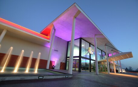 A modern building with a glass entrance and a series of water jets on the ground.