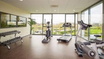 A gym with treadmills, elliptical machines, and dumbbells.