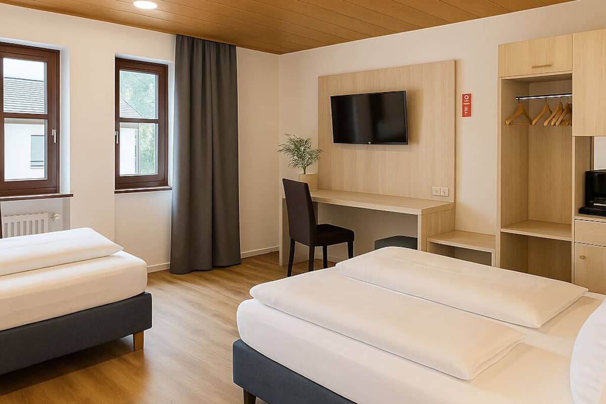 A hotel room with a bed, a desk, a chair, a TV, and a wardrobe.