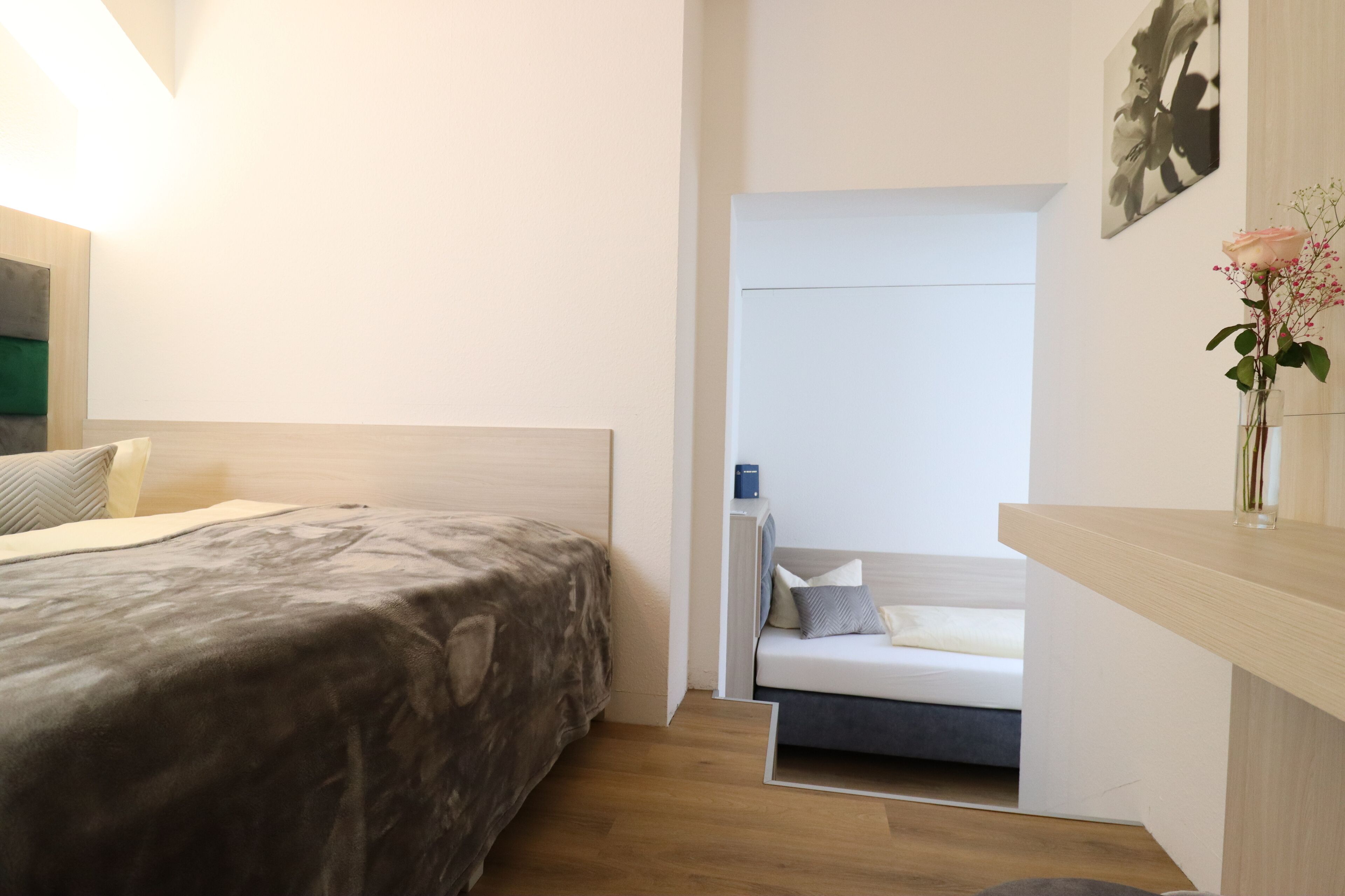 Ein modernes Schlafzimmer mit Bett, Nachttisch und einer kleinen Sitzecke.