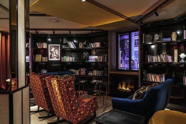 A cozy library with bookshelves, a fireplace, and comfortable seating. - Hotel Vincci Vía 66 (Madrid)
