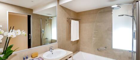 A modern bathroom with a glass-enclosed shower, a sink, and a large mirror.