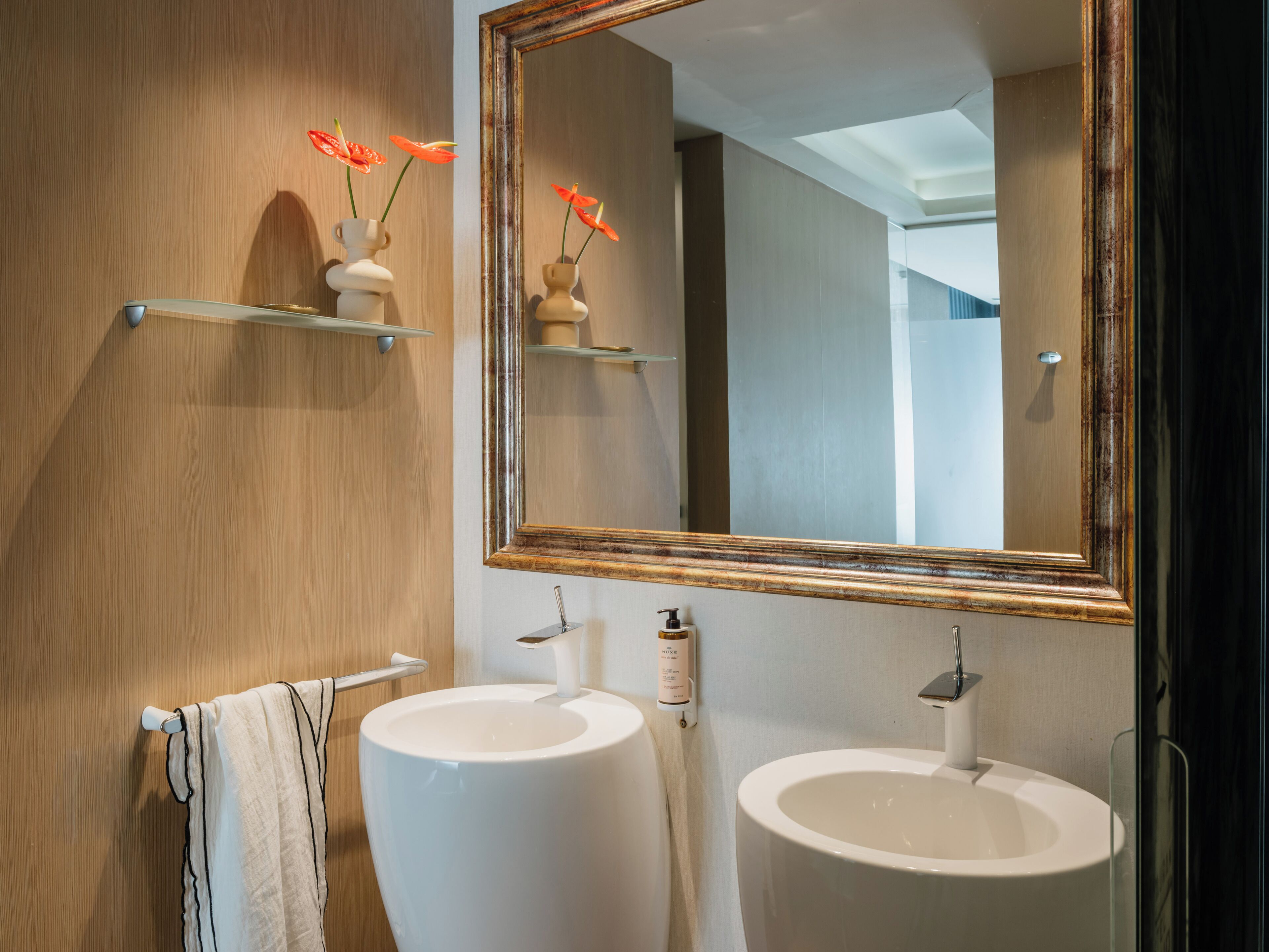 A bathroom with two sinks, a mirror, and a towel rack.