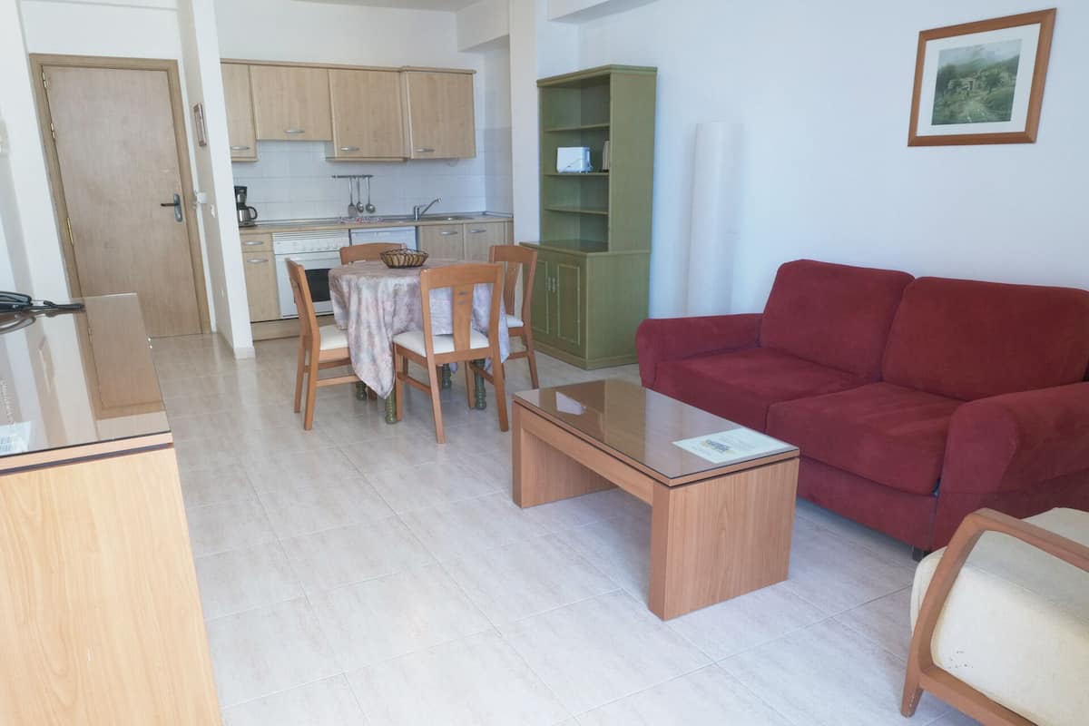 A compact living space with a dining area, kitchenette, and a red sofa.
