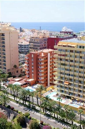 A high-rise hotel with multiple balconies, a swimming pool area, and a view of the sea. - Apartamentos Alta (Puerto de la Cruz)