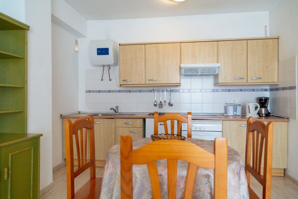A compact kitchen with wooden cabinets, a built-in oven, and a coffee maker. - Apartamentos Alta (Puerto de la Cruz)