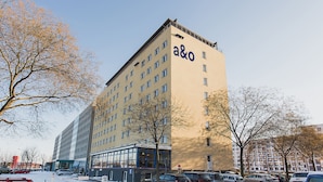 Un edificio de varios pisos con un llamativo letrero 'a&o', que presenta un diseño arquitectónico moderno con grandes ventanales y techo plano.