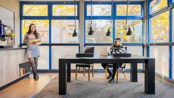 Un espacio de oficina moderno con ventanas amplias, una mesa negra y sillas.