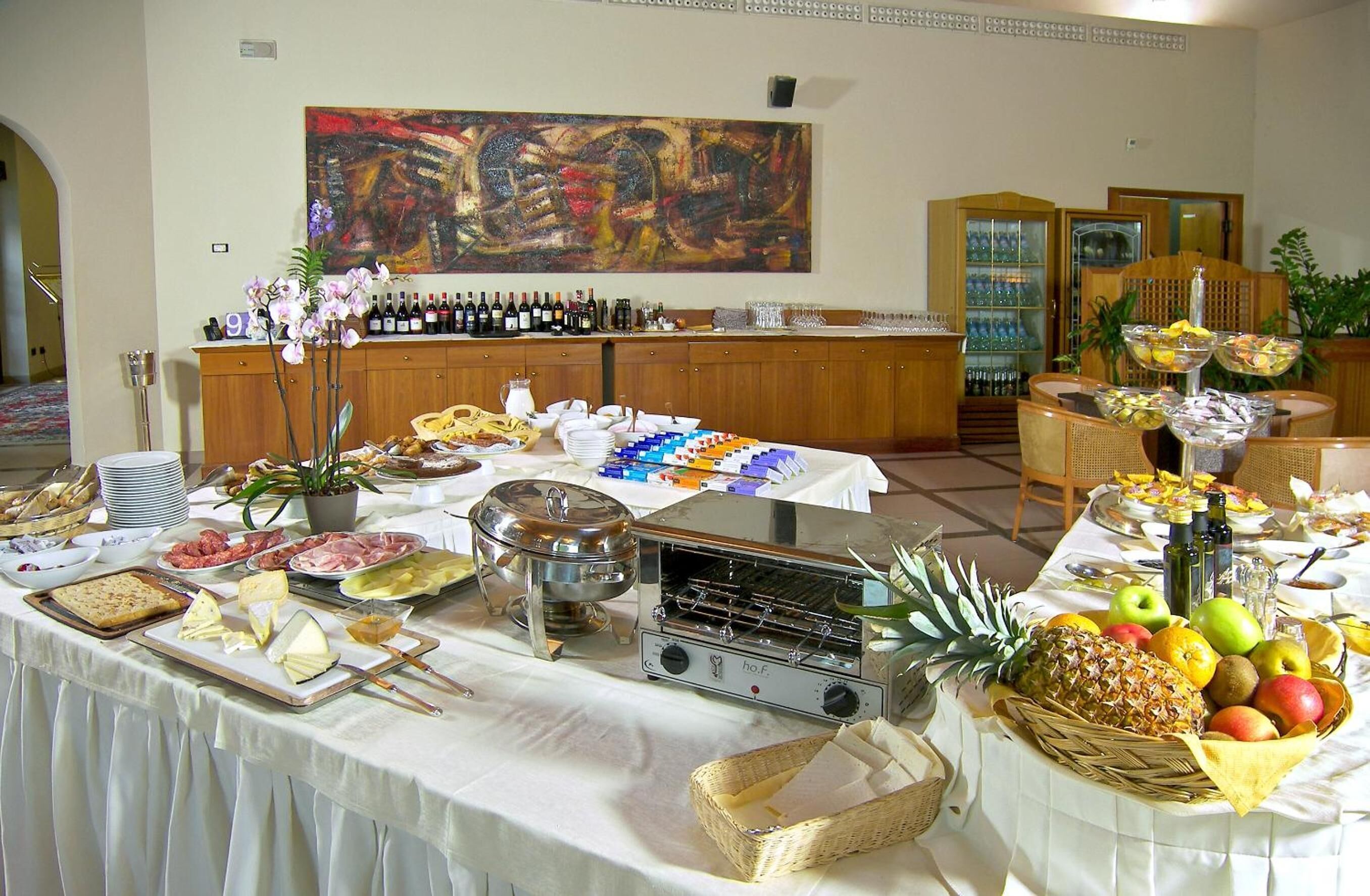 Montaje de bufé con diversos alimentos, un tostador y una selección de vinos.