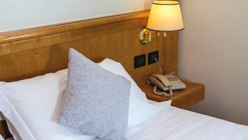 Ein Hotelzimmer mit hölzernem Kopfteil, einer Nachttischlampe, einem Telefon und einem Kissen.