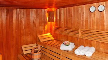 A wooden sauna with benches, towels, and a bucket.