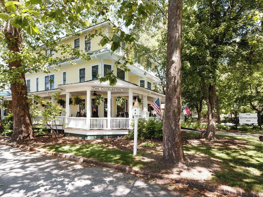 A two-story building with a porch, labeled "The Charleston Inn," surrounded by trees and a well-maintained lawn.