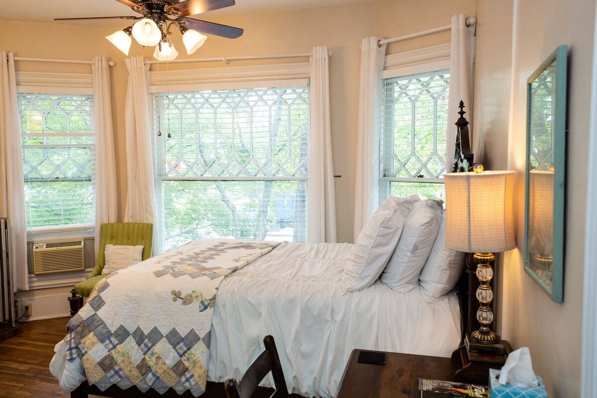 Une chambre à coucher avec un lit, une chaise, une table et une lampe.