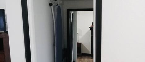 Un pasillo con suelo de madera, marco de puerta blanco y un espejo que refleja a alguien tomando una fotografía.