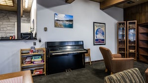 Een kamer met een piano, een boekenkast, een stoel en een poster aan de muur.