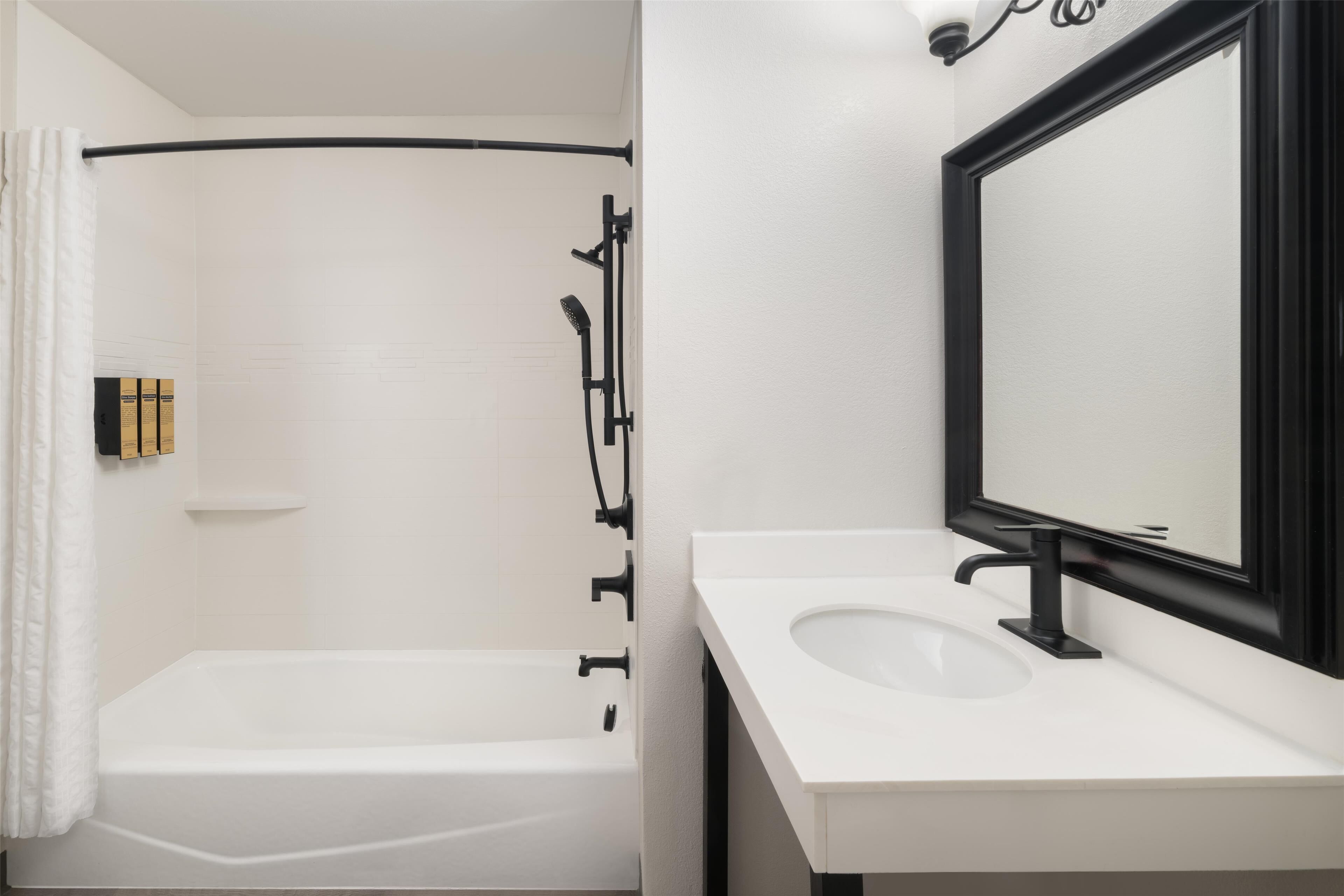 A modern bathroom with a bathtub, a sink, and a mirror.