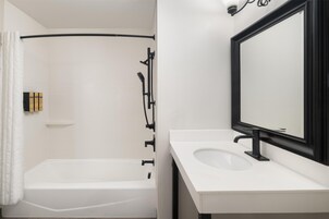 A modern bathroom with a bathtub, a sink, and a mirror.