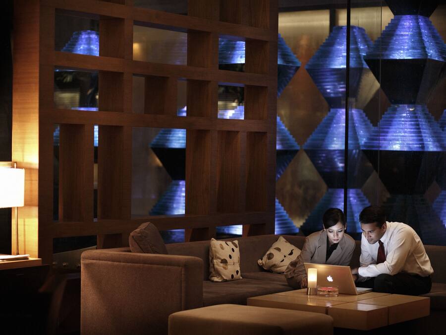 A modern interior with a wooden partition, a sofa with patterned cushions, and a laptop on a table.