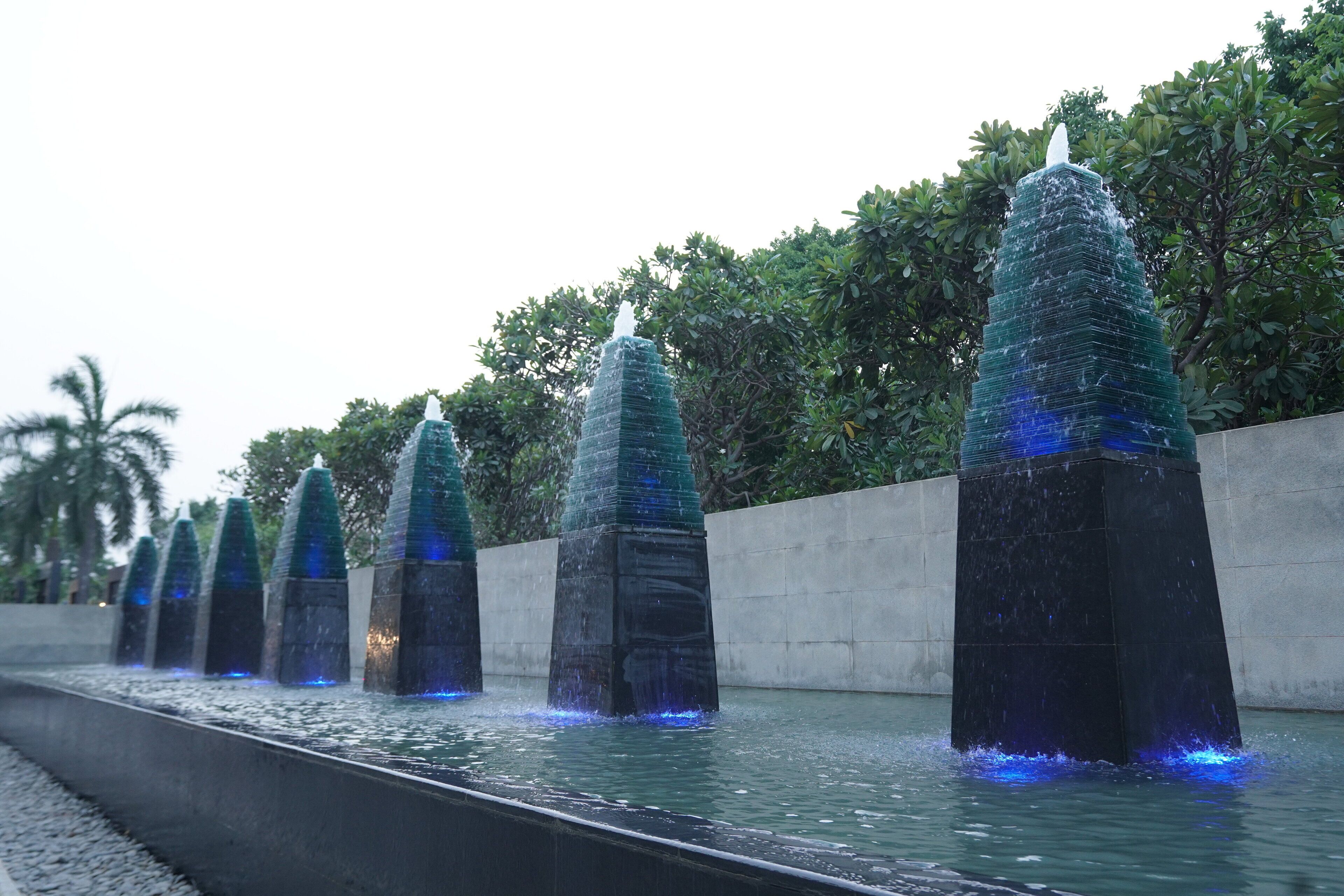 Una serie de fuentes de agua con diseño moderno, alineadas a lo largo de un sendero.