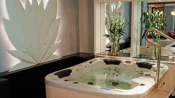 A modern bathroom with a large bathtub, a mirror, and a decorative wall panel.
