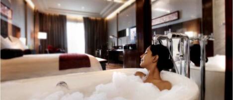 A luxurious bathroom with a bathtub filled with bubbles, a mirror, and a modern design.
