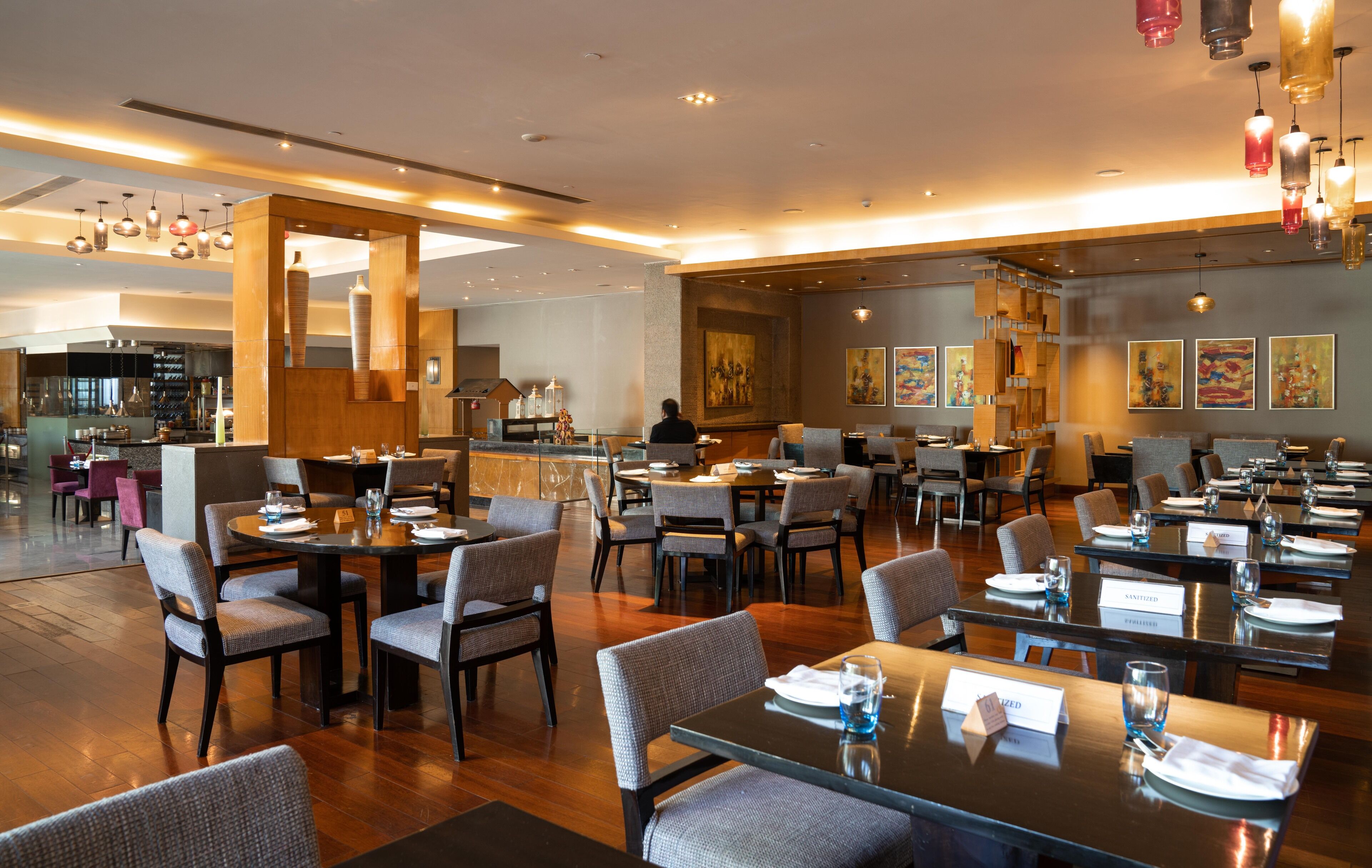 A modern restaurant with multiple dining areas, wooden accents, and artwork on the walls.