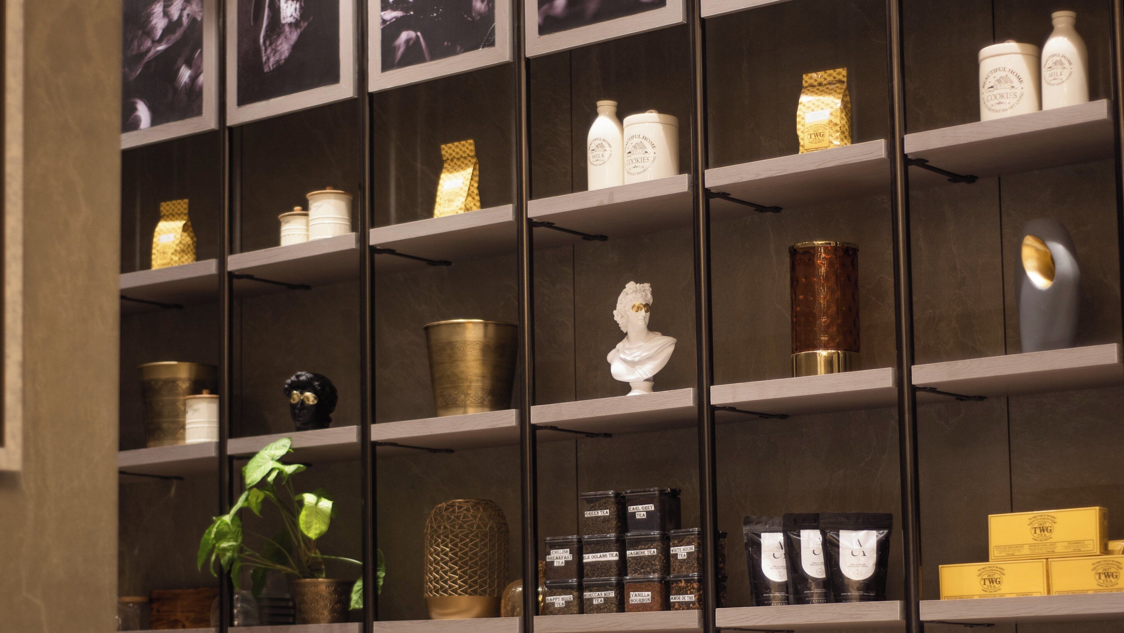 A neatly organized shelf with various tea products, a bust sculpture, and some decorative items.