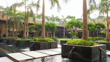A water feature with multiple fountains and palm trees in a courtyard.