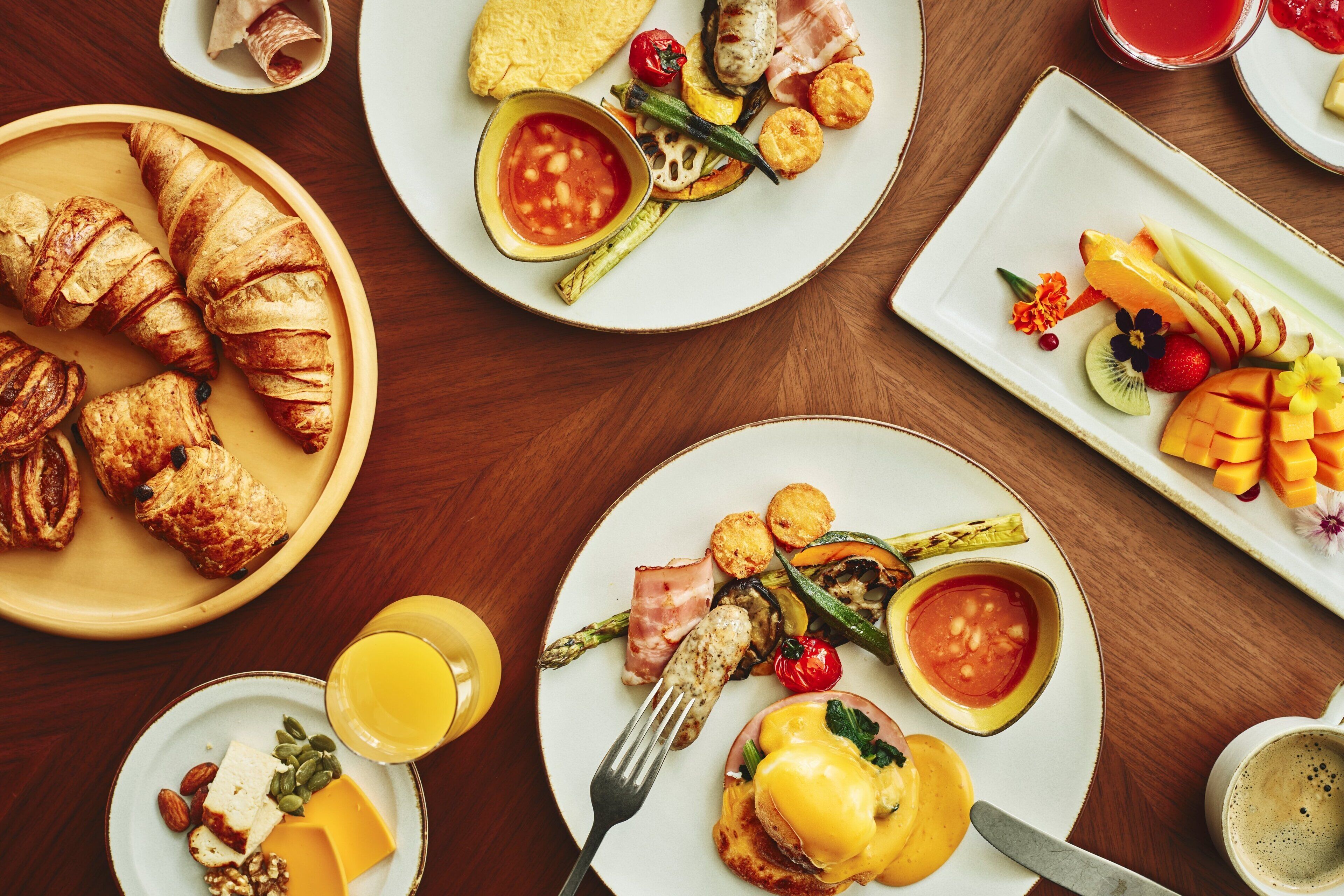 A breakfast buffet with croissants, cheese, fruits, and vegetables.