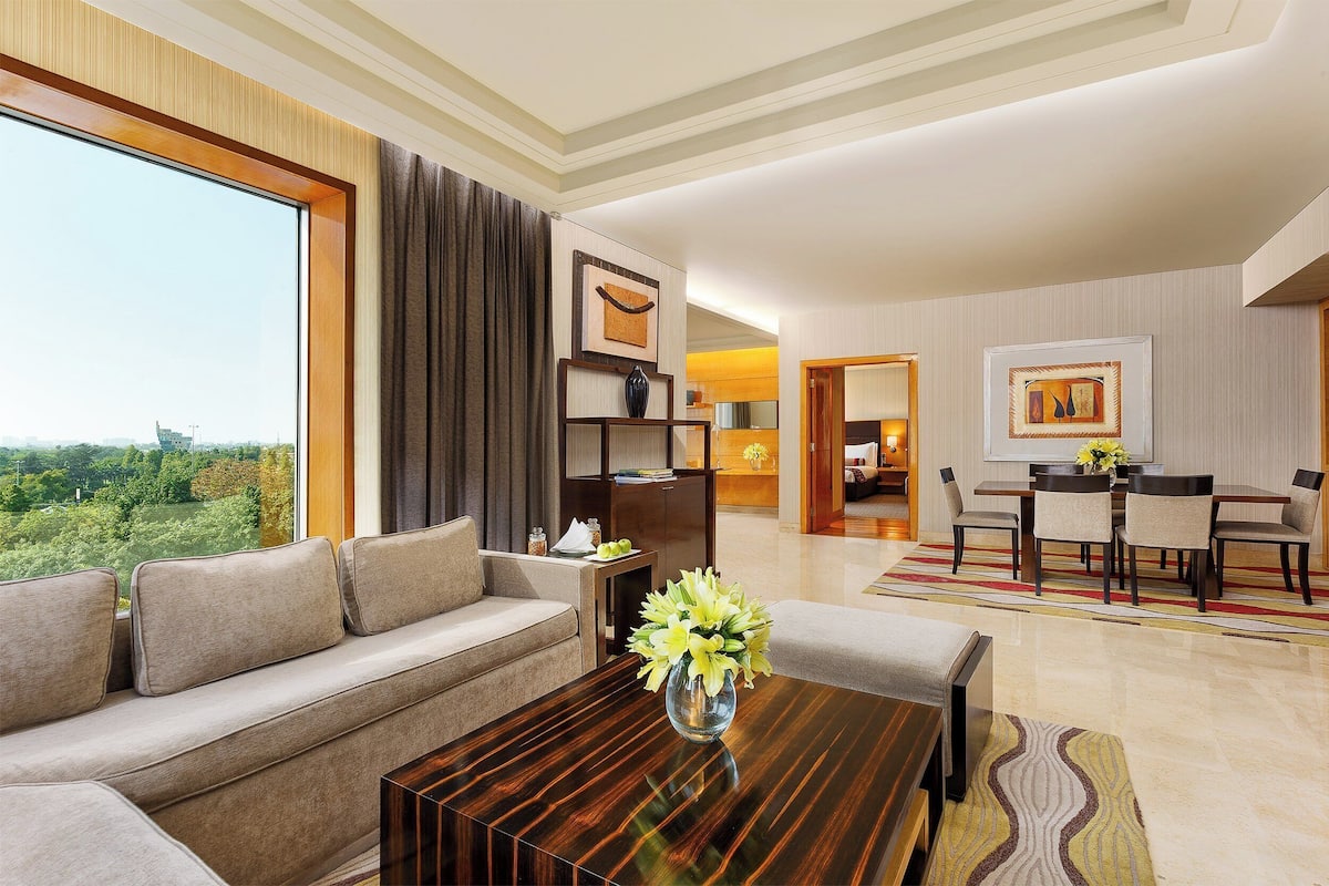 A modern living room with a sofa, a coffee table, and a dining area with a table and chairs.