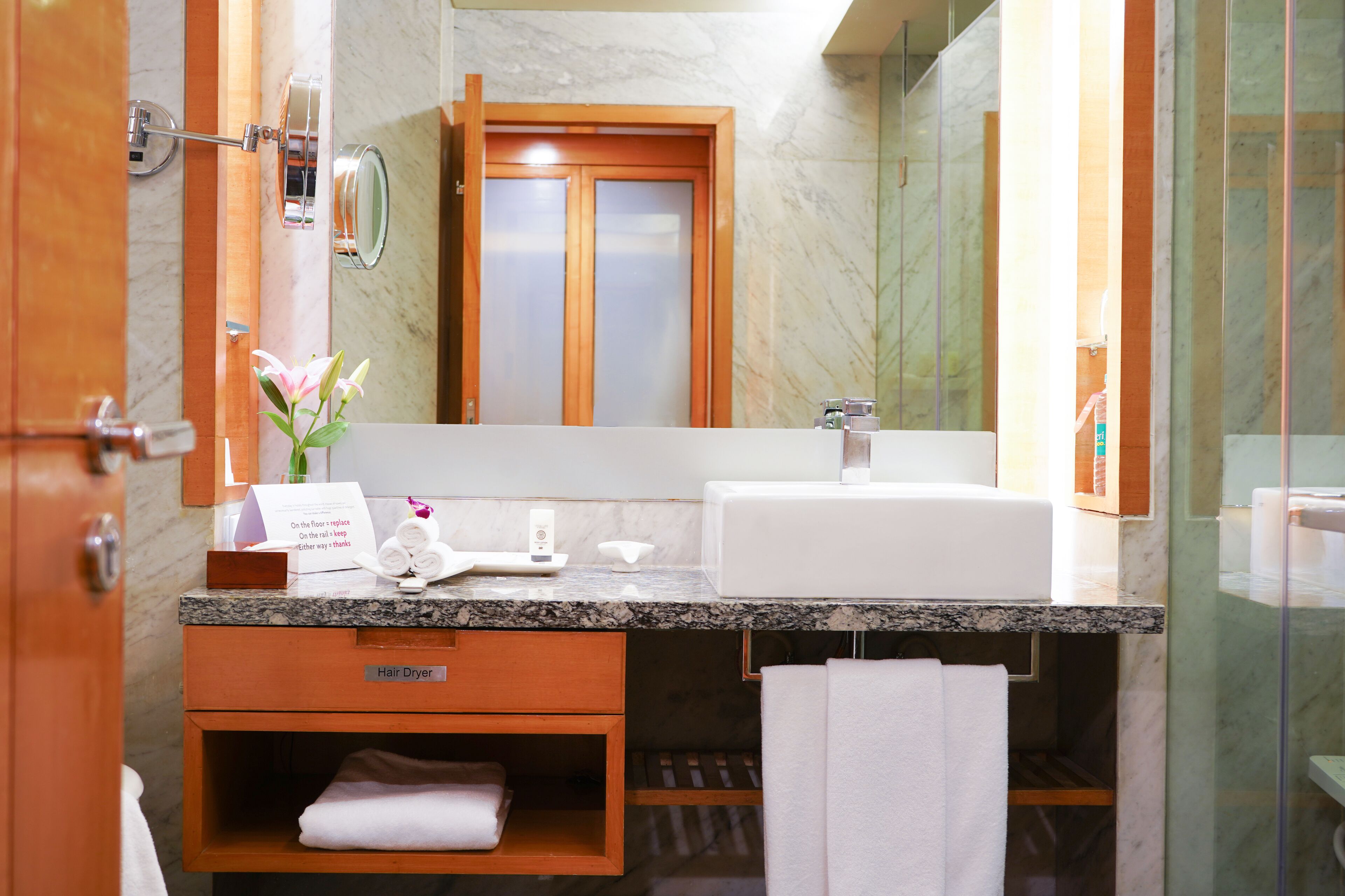 A bathroom with a marble sink, wooden vanity, and a mirror.