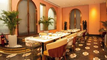 A dining area with a long table, chairs, and potted plants.