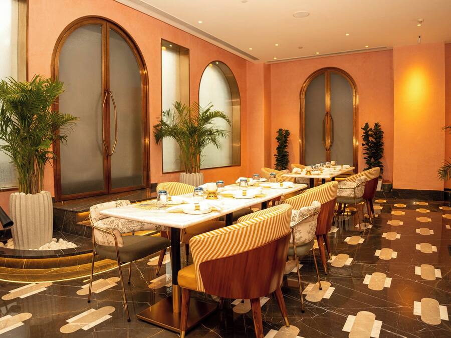 A dining area with a long table, chairs, and potted plants.