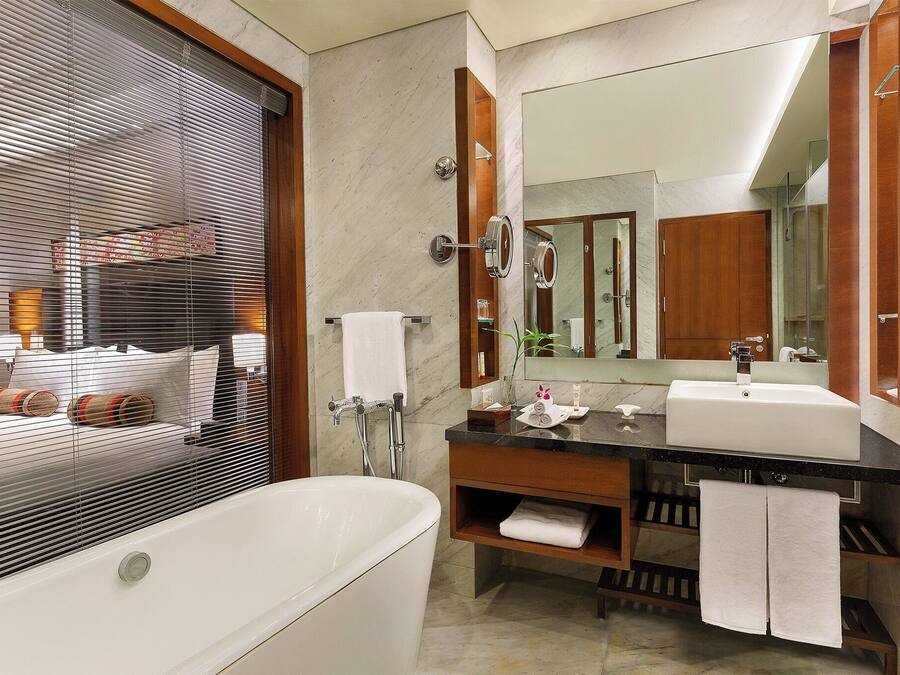 A modern bathroom with a bathtub, a double sink vanity, and a large mirror.