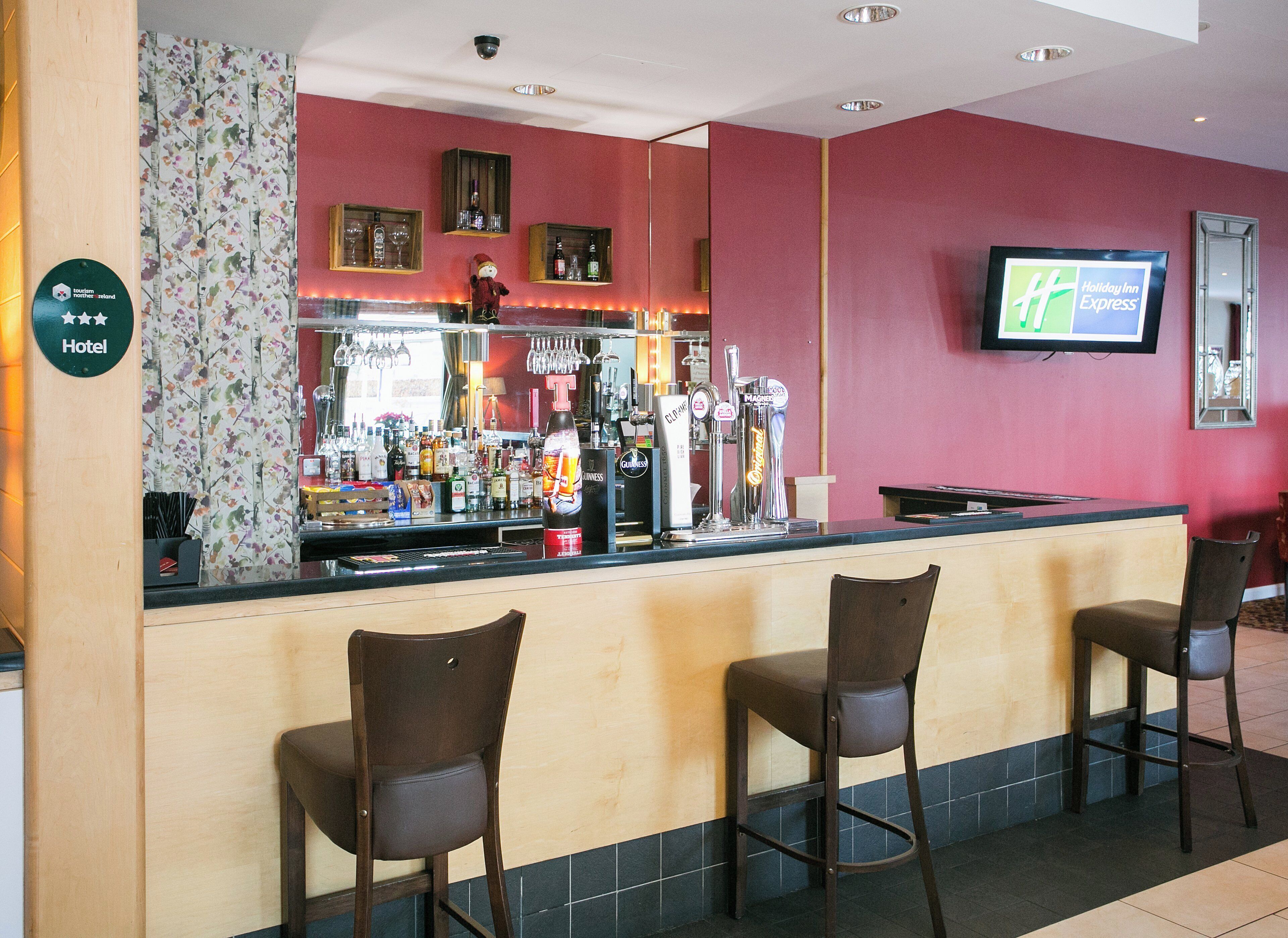Eine Bar mit einer Theke, mehreren Zapfhähnen und Barhocker.