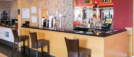 A bar area with a counter, stools, and a Christmas tree.