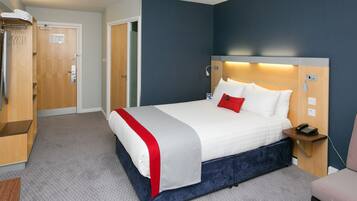 A hotel room with a bed, a bedside table with a phone, a wardrobe, and a door.