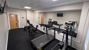 Un gimnasio con cintas de correr, elípticas y una bicicleta estática.